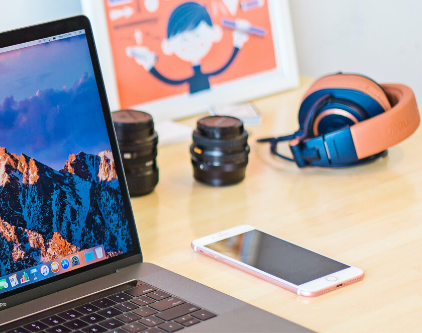 A desk with iPhone, headphones and open laptop
